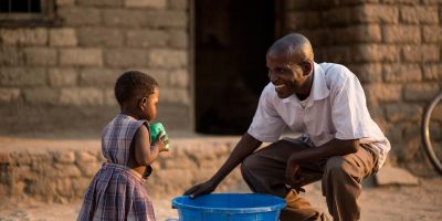 Gordon Laimoni (champion masculin) joue avec Emily Mkuzi devant leur domicile dans le district de Ganamba, au Malawi. Au Malawi, 40 000 bébés naissent avec le VIH chaque année. Sans aucune intervention, les deux tiers de ces enfants n’atteindront pas leur premier anniversaire. Grâce aux antirétroviraux, la transmission du VIH de la mère au bébé peut être évitée, mais bien souvent, le premier pas vers la santé passe par le soutien de la communauté. Au Malawi, les hommes sont souvent les principaux décideurs à tous les niveaux du ménage. En conséquence, leur influence peut grandement affecter les attitudes et les comportements de leur partenaire. Les données montrent que si les hommes comprennent l’importance des services de santé dès le début de la grossesse, le couple est plus susceptible de subir un test de dépistage du VIH et que les femmes enceintes et vivant avec le VIH sont plus susceptibles de s’inscrire à la PTME. Ainsi, avec le soutien du ministère canadien des Affaires étrangères, du Commerce et du Développement (MAECD), l'UNICEF et le ministère de la Santé du Malawi ont lancé le modèle de champion masculin en 2012. Grâce à ce programme, les motivateurs masculins encouragent d'autres hommes à s'impliquer dans le santé de leurs partenaires. Les hommes qui accompagnent leur femme pour rechercher des services de santé sont connus sous le nom de « champions ». À ce jour, 3 400 motivateurs masculins répartis dans six districts ont été formés. Selon Beatrice Chigamba, infirmière en chef à l'hôpital du district de Chikwawa. « Cela semble avoir un effet considérable sur le nombre de femmes testées pour le VIH pendant la grossesse, ce qui, en fin de compte, diminue le nombre de bébés nés avec le VIH. » UNICEF/UNI173428/Schermbrucker