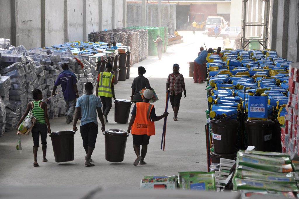 Le 28 janvier, des ouvriers transportent de grands seaux et d'autres articles faisant partie des kits scolaires de prévention et de contrôle des infections (PCI), dans un entrepôt de Monrovia, la capitale. Les logos de l'UNICEF et de l'USAID (l'Agence des États-Unis pour le développement international) – qui ont contribué au financement des kits – sont visibles sur certains seaux et autres articles. Les kits contiennent également des seaux avec des robinets, des gants et des bottes en caoutchouc, des pistolets thermiques, du chlore et des pulvérisateurs de chlore, du savon, des balais et d'autres articles permettant aux écoles de mettre en œuvre les protocoles de sécurité stricts qui ont été élaborés pour la reprise des cours dans le contexte de la Épidémie d’Ebola. L'UNICEF a acheté, conditionne et expédie plus de 7 000 kits IPC dans plus de 4 000 écoles du pays. Le Libéria, avec la Guinée et la Sierra Leone, continue de connaître une transmission généralisée et intense de la MVE. Fin janvier/début février 2015 au Libéria, alors que les écoles se préparent à rouvrir, l'UNICEF et ses partenaires contribuent à réduire autant que possible le risque de maladie à virus Ebola ( MVE). Le soutien comprend la formation des enseignants à mettre en œuvre des mesures de sécurité, telles que des contrôles quotidiens de la température, et la fourniture de thermomètres et de kits de lavage des mains aux écoles. En raison de la MVE, les écoles publiques de Guinée, du Libéria et de la Sierra Leone sont restées fermées après les vacances de juillet à août, privant 5 millions d'enfants de mois d'éducation. Alors que les écoles continuent de fermer leurs portes au Libéria et en Sierra Leone, l'UNICEF travaille avec les gouvernements et les communautés pour préparer leur éventuelle réouverture. Les écoles devraient rouvrir au Libéria le 16 février. UNICEF/UNI178619/Ratnam