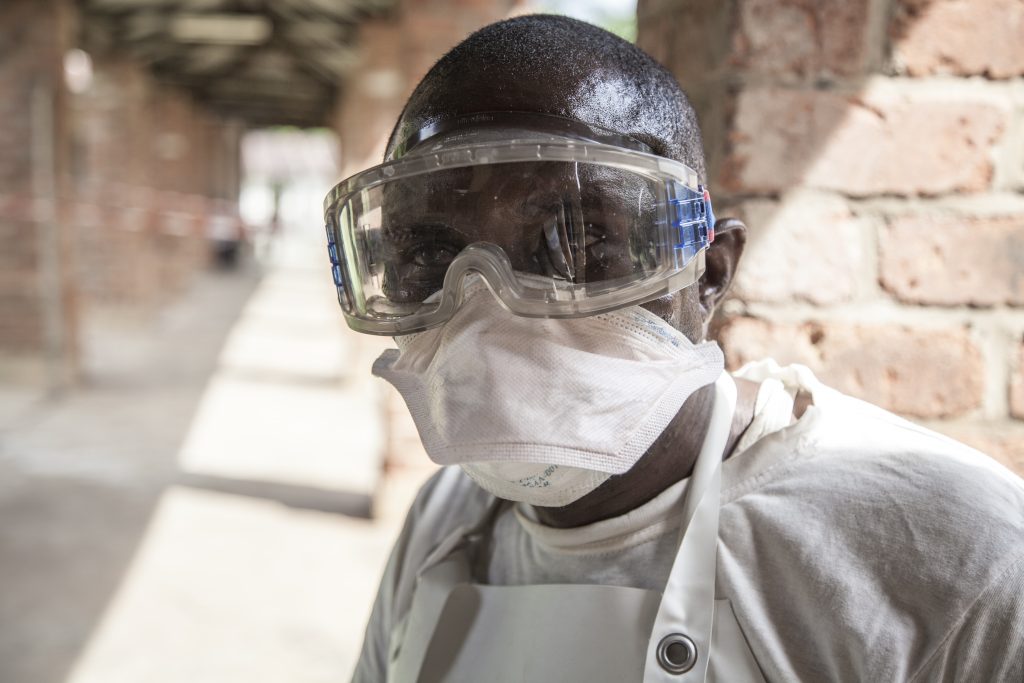 On 12 May 2018 in Democratic Republic of Congo (DRC), a health worker at Bikoro Hospital, the epicenter of the latest Ebola outbreak in the DRC. Bikoro Hospital has sealed off a ward to diagnose suspected Ebola patients and provide treatment. The DRC has experienced nine known Ebola outbreaks.
Following the announcement by the Government of the Democratic Republic of the Congo (DRC) on 8 May 2018 of a new Ebola outbreak in Equateur Province, UNICEF has mobilised its teams to help contain the spread of the disease. The outbreak was declared in the Bikoro Health Zone, located more than 100 kilometers south of the provincial capital of Mbandaka. A UNICEF team with two doctors, a specialist in water, sanitation and hygiene as well as a specialist in community communication left today from Mbandaka to assess the extent of the epidemic and begin implementing the response, alongside the Government and the World Health Organization (WHO). This is the ninth Ebola outbreak in the country since 1976. UNICEF supports the Government in its coordination of the response both from the country’s capital Kinshasa as well as in the affected area. UNICEF has been active in the Equateur Province for many years. Based on its experience in previous Ebola epidemics, UNICEF is focusing its response on communication activities in the communities to protect people from the disease and on water supply, hygiene and sanitation to prevent the spread of the disease. UNICEF has already sent a total of 45 kg of chlorine, five sprays, 50kg of soap and 28,000 water purification tablets to the area, as well as 600 posters and 6,000 leaflets to educate affected communities. © UNICEF/UN0209049/Naftalin