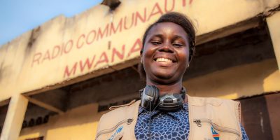 A smiling woman with earphones around her neck