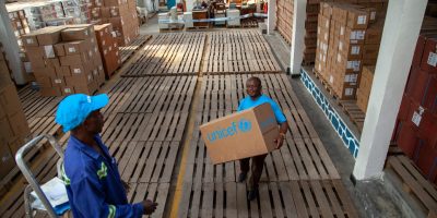 On 9 August 2018, Patrick Lonji, UNICEF Supply and Logistics Officer in Goma, North Kivu, DRC, carries supplies through a UNICEF warehouse.
Following the 1 August 2018 announcement by the Government of the Democratic Republic of the Congo (DRC) of a new Ebola Virus Disease (EVD) outbreak in North Kivu, UNICEF has mobilized its teams to help contain the spread of the disease and protect children. The impact of an outbreak on children can be far reaching. It’s known from earlier outbreaks in the DRC as well as in West Africa that children can be affected in various ways. Children can themselves be infected by the disease, but the impact goes beyond; it impacts their families and communities as children can lose their parents, care-givers and teachers. Access to basic services such as health care and education can become severely compromised. Also, children who are infected or whose relatives are, face stigmatization and social exclusion.
The Congolese Government has activated its response plan and called its partners, including UNICEF, to participate in the response. UNICEF has deployed a team to Beni for the response, including health specialists, communication specialists and a water, sanitation and hygiene specialist from the Ebola-response team in the Province of Equateur. Health, water, sanitation and hygiene and communication supplies have been sent to the affected areas including 300 laser thermometers to monitor the health conditions of people in the affected region and 2,000 kg of chlorine to treat water to help contain the spread of the disease. As at 14 August 2018, UNICEF has installed 35 chlorination points, as well as handwashing units in 45 public places and in health facilities in the affected areas of Beni and Mangina in North Kivu. UNICEF has supported the distribution of prevention posters and leaflets, and worked with communities, in public places and with local radio stations to promote safe hygiene and sanitation practices that help cont UNICEF/UN0228761/Naftalin