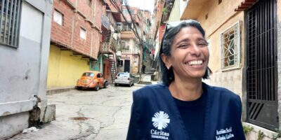 Femme souriante portant une veste bleue de Caritas, debout dans la rue